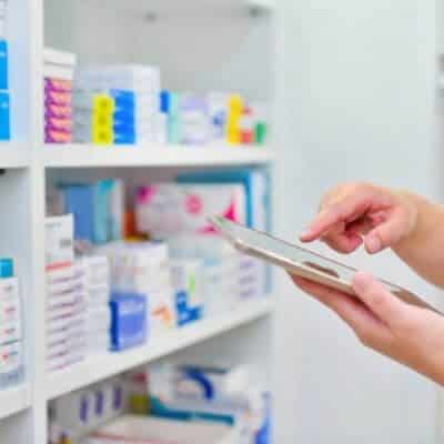 a person stands in a pharmacy, holding a tablet